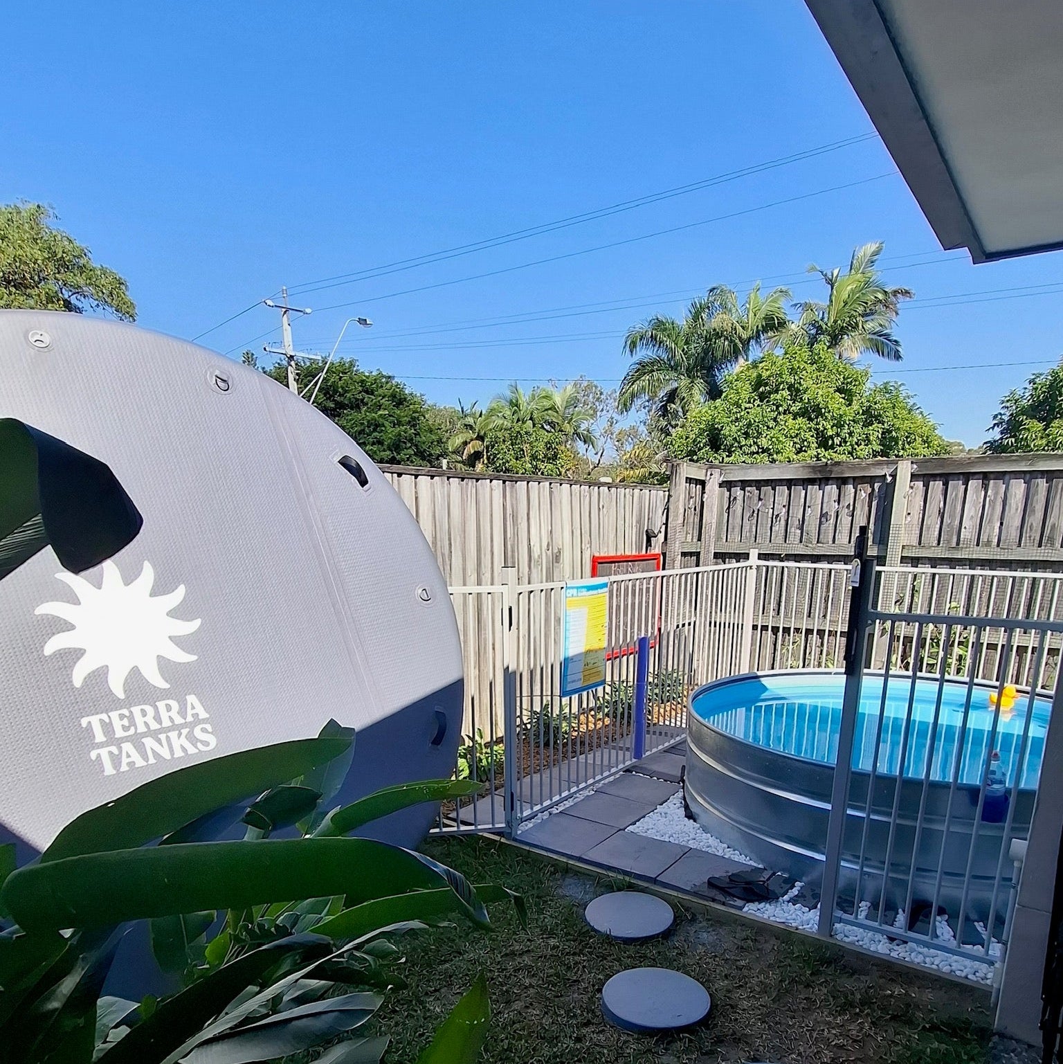 Backyard with stock tank pool and fencing under clear blue sky
