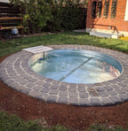 Small stock tank pool with stone patio in a backyard setting