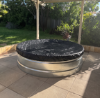 Metal stock tank pool with a black cover on a paved patio area